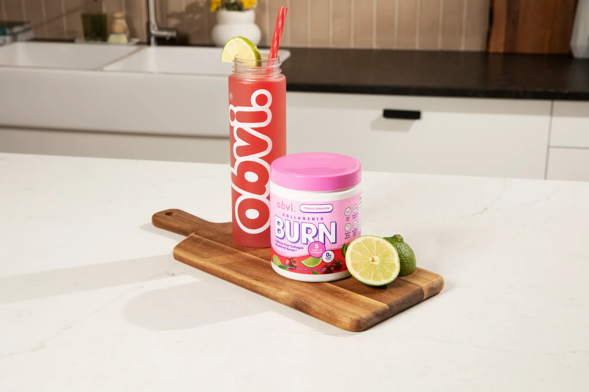 Obvi Collagenic Burn Powder Cherry Limeade tub and bottle on white marble kitchen counter